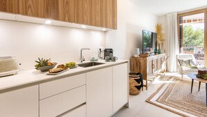 Een moderne keuken met witte kasten, een ingebouwde oven en een koffieapparaat.