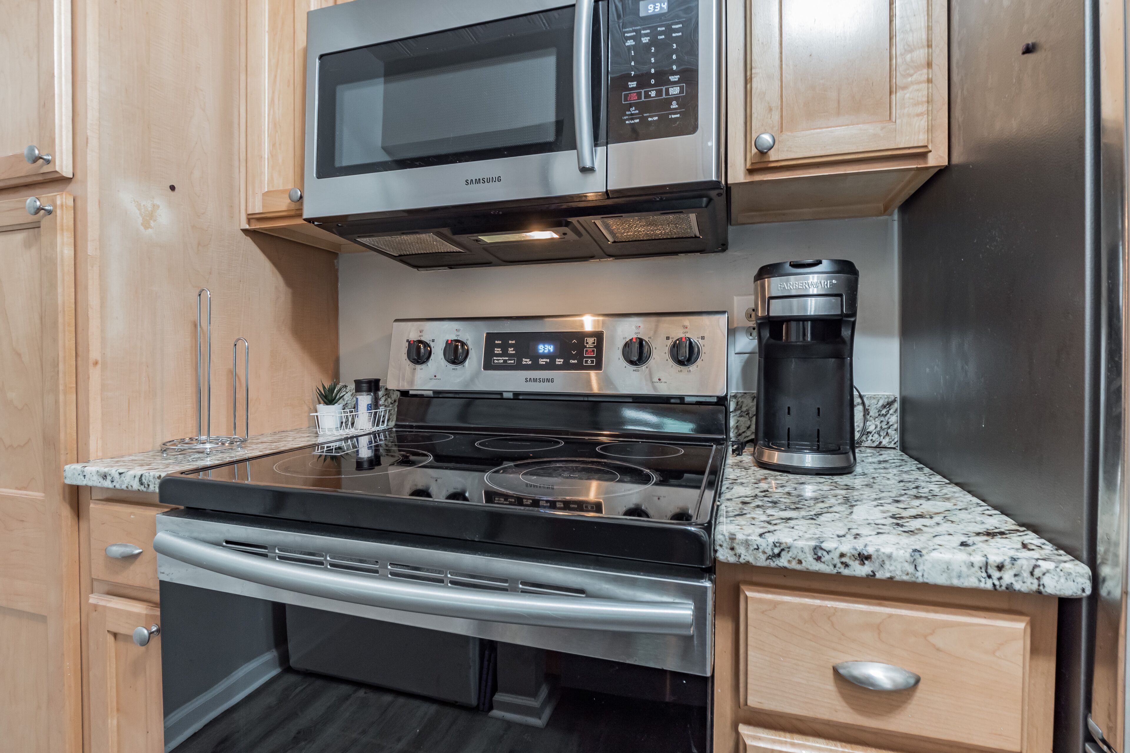 A kitchen with stainless steel appliances, including a microwave, oven, and coffee maker.