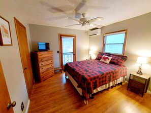 Un dormitorio con cama, cómoda, ventilador de techo y ventana con persianas.