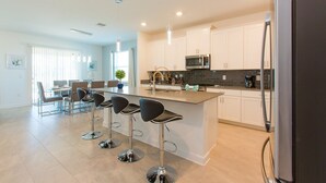 A modern kitchen with white cabinets, stainless steel appliances, and a central island with bar stools.