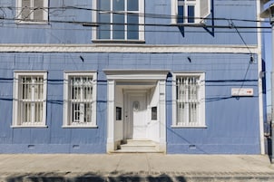 Un edificio azul con marcos blancos en las ventanas y una puerta blanca.