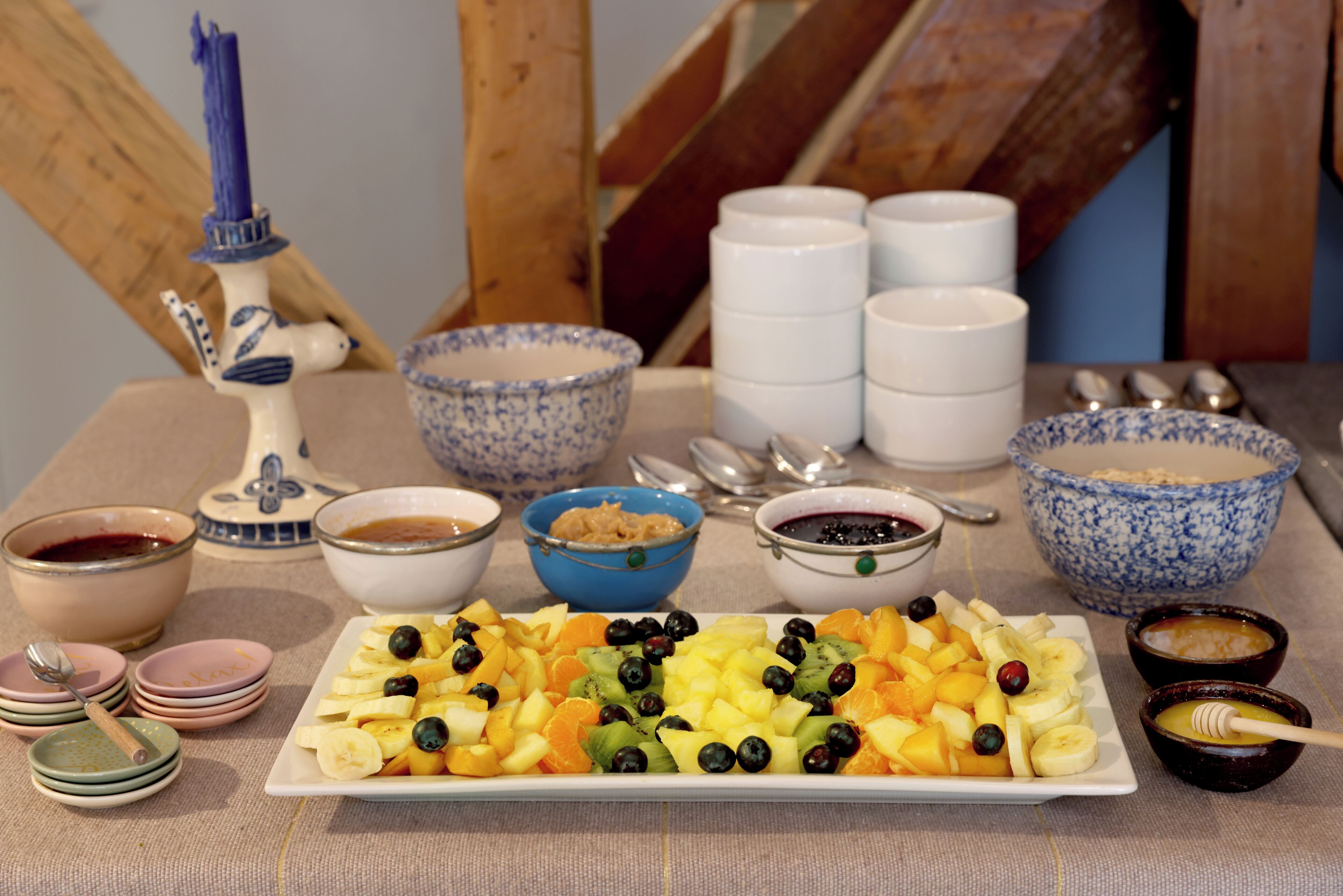 A table with a fruit platter, bowls of various foods, and a decorative candle.