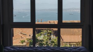 A view through a window with a view of the sea and distant cityscape. - Casablu Hotel (Valparaiso)