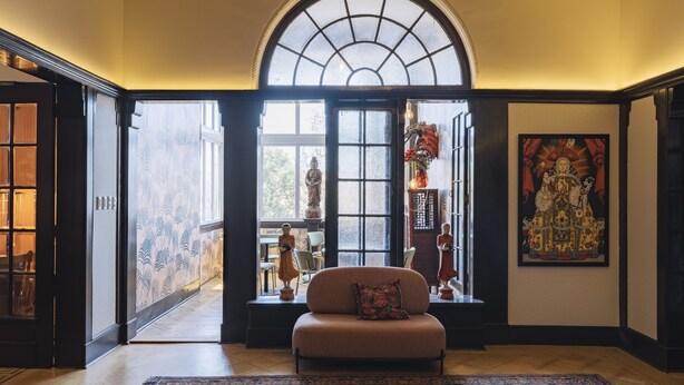 A spacious room with a large arched window, a sofa, and a rug. - Casablu Hotel (Valparaiso)