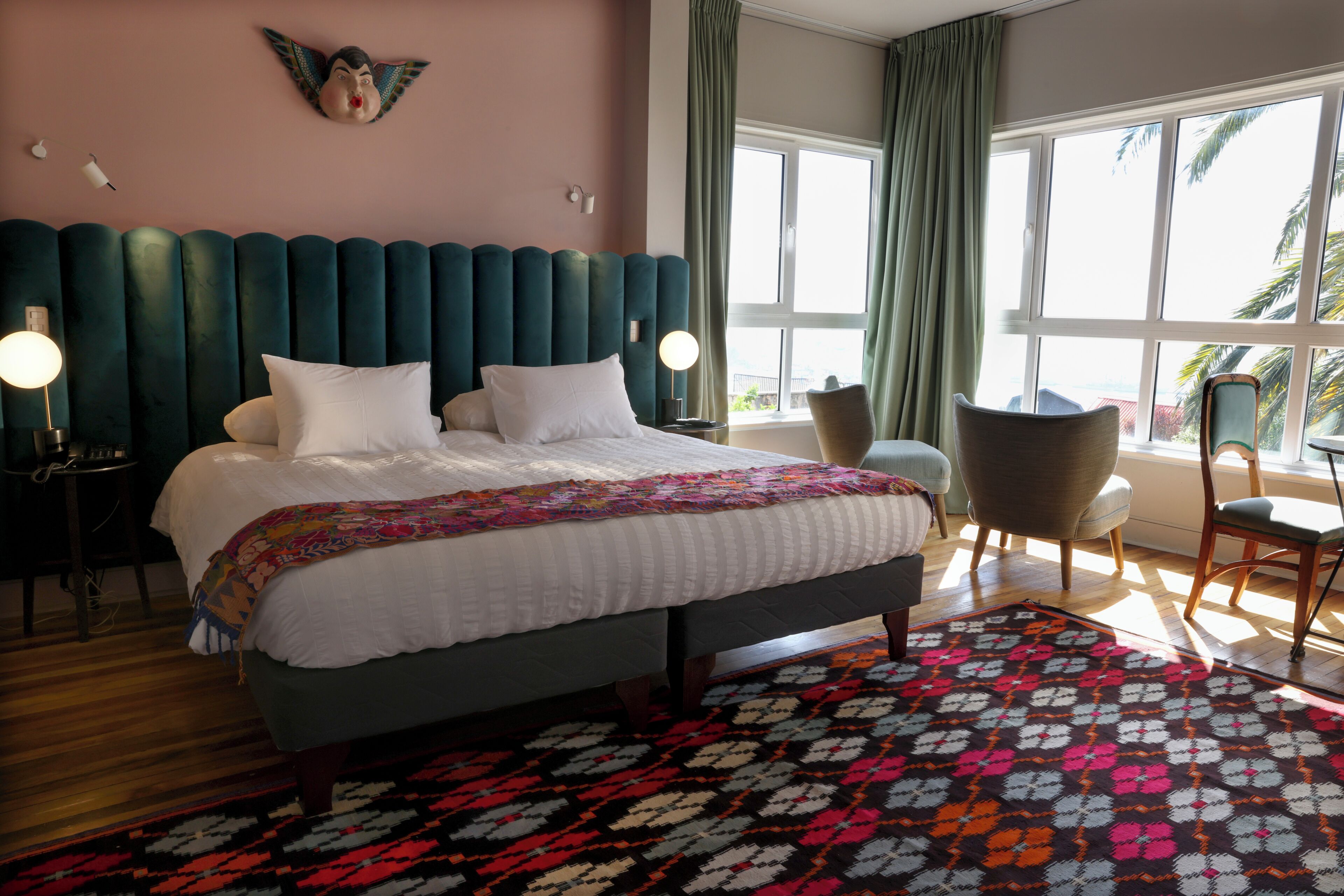 Une chambre d’hôtel avec un lit, une chaise, un bureau et une grande fenêtre.
