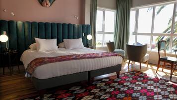 Une chambre d’hôtel avec un lit, une chaise, un bureau et une grande fenêtre.