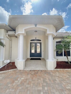 A house with a covered entrance, a dark blue door, and a brick pathway leading to the front. - The happy family Hideaway (Port Charlotte)
