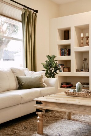 A living room with a white sofa, a coffee table, and a bookshelf. - The happy family Hideaway (Port Charlotte)