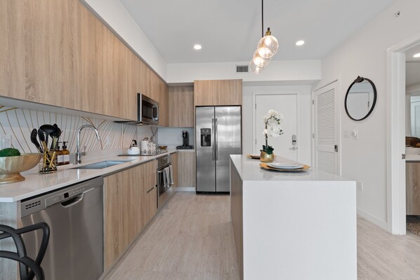 Una cocina moderna con armarios de madera, electrodomésticos de acero inoxidable y encimera blanca.