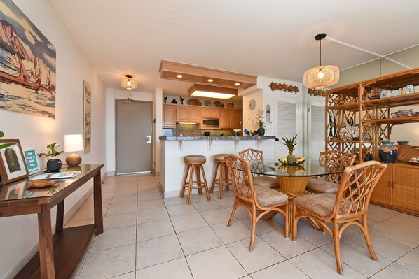 A modern kitchen with wooden cabinets, a central island, and a dining area with wicker chairs.