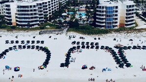 Ein Strandhotel mit mehreren Hochhäusern, einem Sandstrand und einem Swimmingpool.
