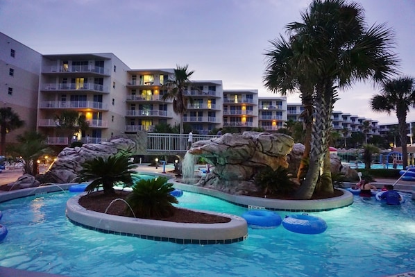 Relax by the resort pool, surrounded by multiple pools and a central island with a waterfall.