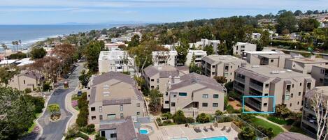 A residential area with modern buildings, a swimming pool, and a view of the ocean.