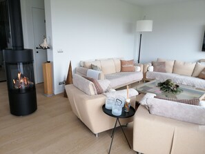 Una sala de estar moderna con chimenea, sofás, una mesa de centro y una lámpara.