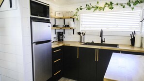 Een koelkast, een magnetron, kookgerei, borden en bestek, kruiden