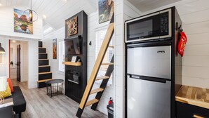 Eine moderne Küche mit einem Edelstahl-Kühlschrank, Holzregalen und einer einzigartigen Holzleiter-Treppe.