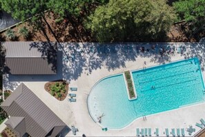 An aerial view of a swimming pool with lounge chairs and a building.