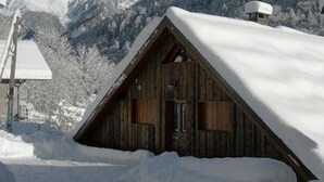 A wooden cabin with a steeply pitched roof, surrounded by snow-covered mountains. - Gite 8 km from the access to Alpe d'Huez large domain (ALLEMOND)