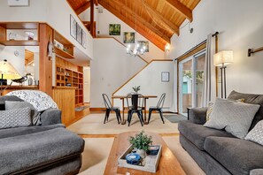 Relax in this inviting living space, featuring a central seating area, dining table, and bookshelf, perfect for unwinding and socializing.