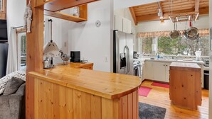 A modern kitchen with wooden accents, a built-in refrigerator, and a window with a view of trees. - Great Sacandaga Waterfront Retreat (Day)