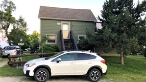 A white SUV parked in front of a green house with a visible garage door and a small porch. - Private Waterfront Loft - an amazing lake view (Leamington)