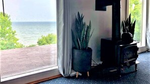 A room with a large window overlooking a body of water, a potted plant, and a black cabinet. - Private Waterfront Loft - an amazing lake view (Leamington)