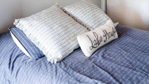 A bedroom with a bed, a wall-mounted light fixture, and a curtain. - Private Waterfront Loft - an amazing lake view (Leamington)