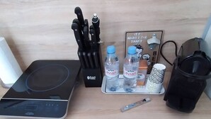 Keittiön työtasolla on Russell Hobbs -merkkinen induktioliesi, veitsiteline, vesipulloja, kahvinkeitin ja muki.