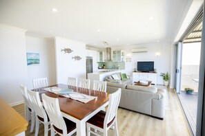 A modern living space with a dining area, kitchen, and a seating area with a television.