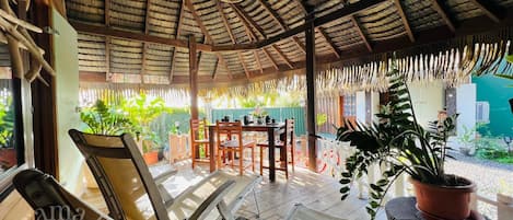 A covered outdoor seating area with wooden furniture and potted plants.