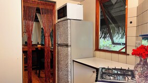 A kitchen with a refrigerator, a stove, and a window with a view of greenery. - Orama Lodge Bora Bora - Le Fare  (Bora-Bora)