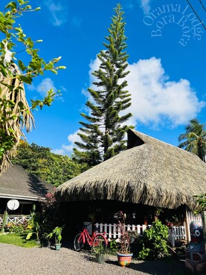 A thatched-roof hut with a bicycle parked in front, surrounded by greenery and a clear blue sky. - Orama Lodge Bora Bora - Le Fare  (Bora-Bora)