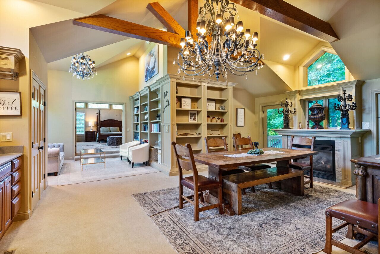 A spacious living area with a large wooden dining table, a chandelier, and a fireplace.