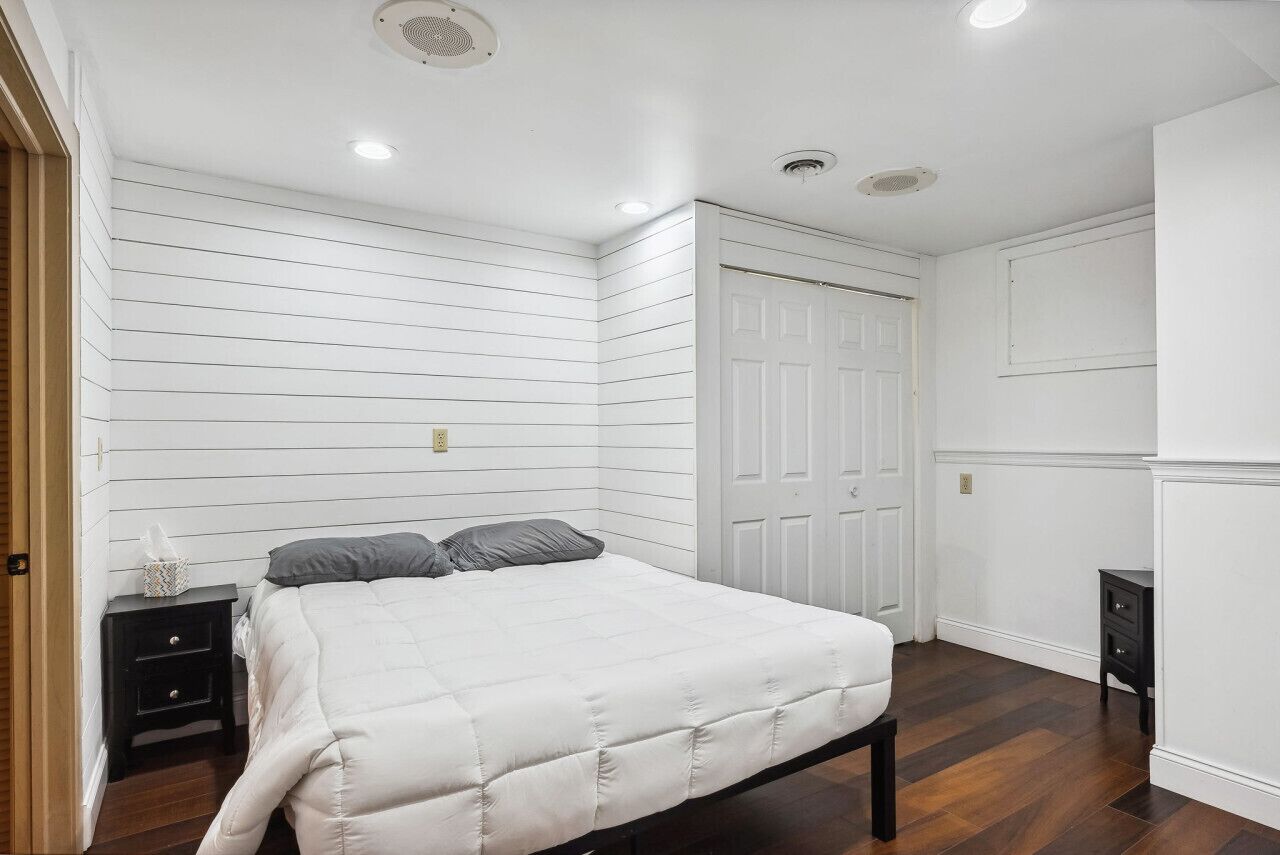 A bedroom with a bed, a nightstand, a dresser, and a door.