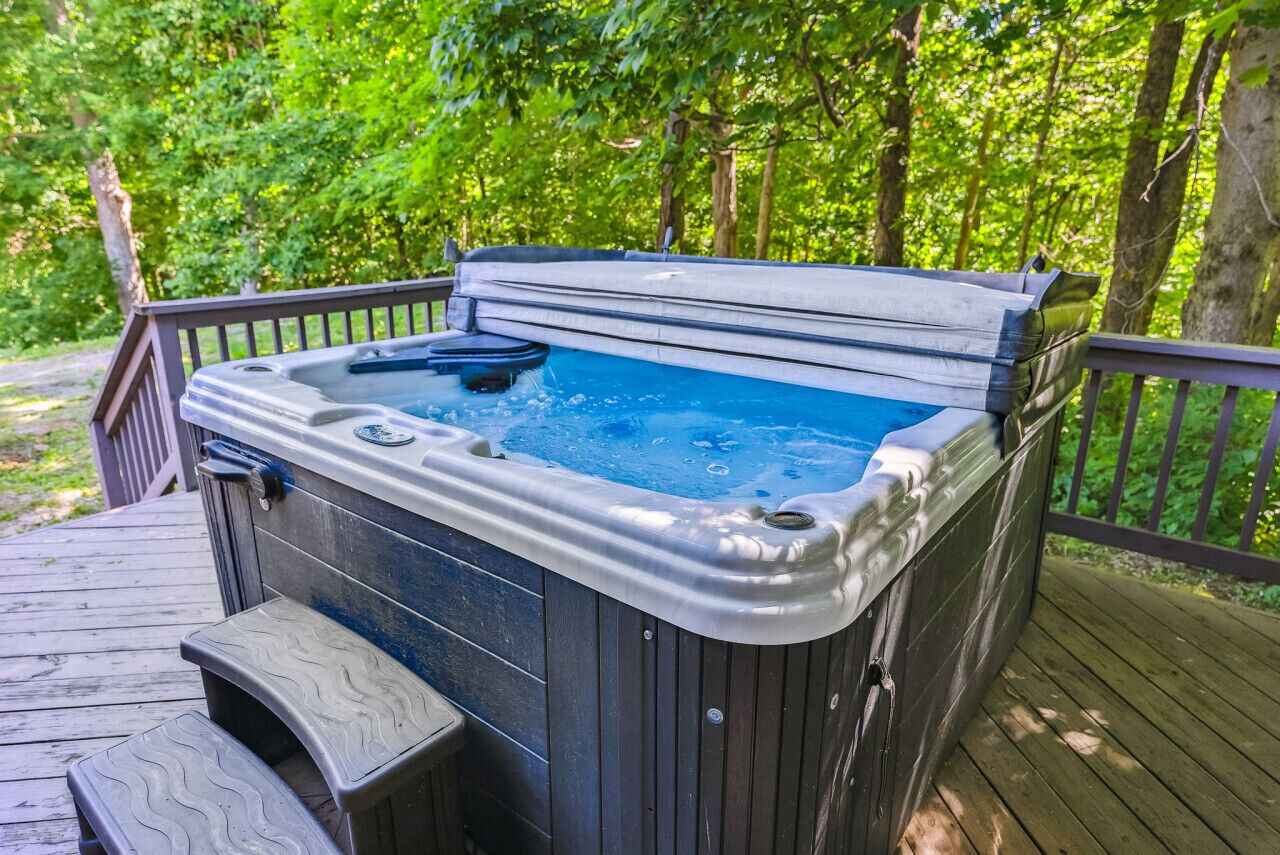 A hot tub on a wooden deck surrounded by trees.