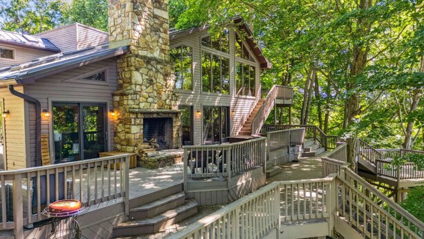 A multi-level outdoor deck with stone and wood structures, surrounded by trees.