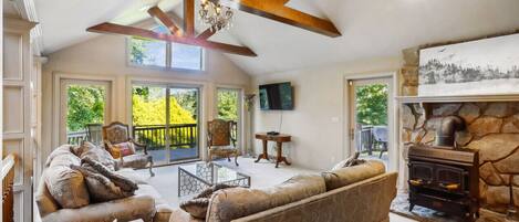 A spacious living room with a fireplace, comfortable seating, and large windows.