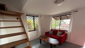 A room with a wooden staircase, a red sofa, and a wooden coffee table. - Stunning one bed/bath unit. Breathtaking ocean/jungle views with infinity pool! (Quepos)