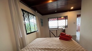 A bedroom with a bed, a window with a view, and a table with towels. - Stunning one bed/bath unit. Breathtaking ocean/jungle views with infinity pool! (Quepos)