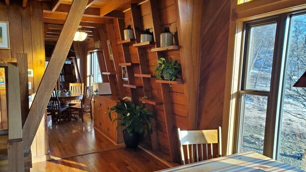 A wooden interior with a dining table, chairs, and a potted plant.