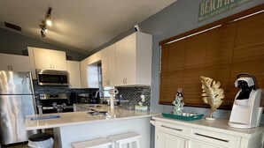 A modern kitchen with white cabinetry, stainless steel appliances, and a wooden accent wall.