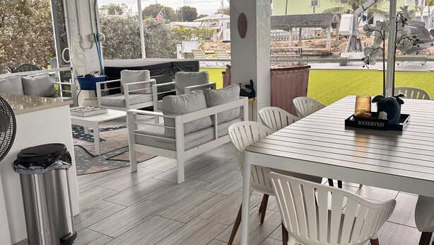 A modern outdoor dining area with a table and chairs, a ceiling fan, and a view of the surrounding landscape.