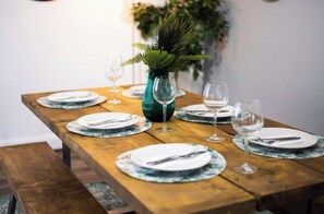 A beautifully set dining table with plates, glasses, and a vase with a plant.