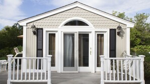 Ein zweistöckiges Haus mit weißer Fassade, einer Veranda mit weißen Geländern und einer Garagentür.