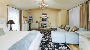 Ein Schlafzimmer mit Bett, Schreibtisch, Sessel, Sofa und einer Deckenleuchte.