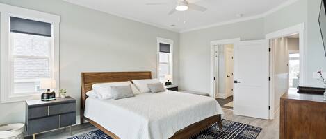 Quarto com cama, mesas de cabeceira, ventilador de teto e tapete estampado.