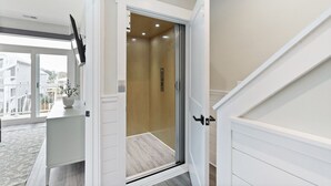 Un interno moderno con una porta scorrevole in vetro che dà su un balcone, una parete bianca e un pavimento in legno.