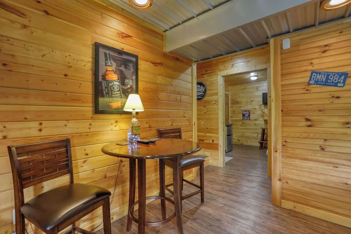 Un interno in legno con un tavolo rotondo e due sedie, una lampada e un quadro appeso al muro.