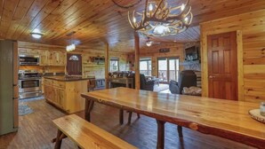 A spacious wooden cabin with a large dining table, a kitchen with modern appliances, and a cozy living area.