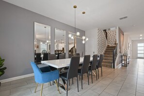 A modern dining area with a white table, black chairs, and a chandelier.